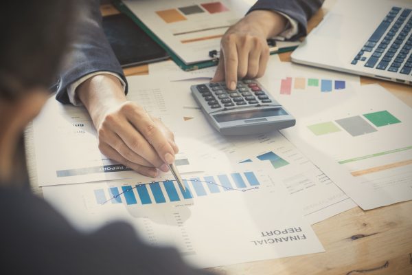 Business man hands at working with financial plan and calculator on wooden desk in office, Group Support concept.